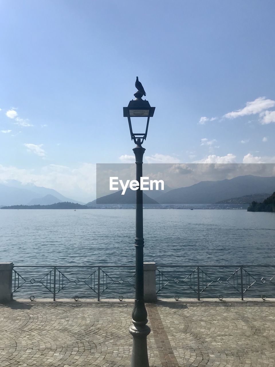 Street light by lake against sky