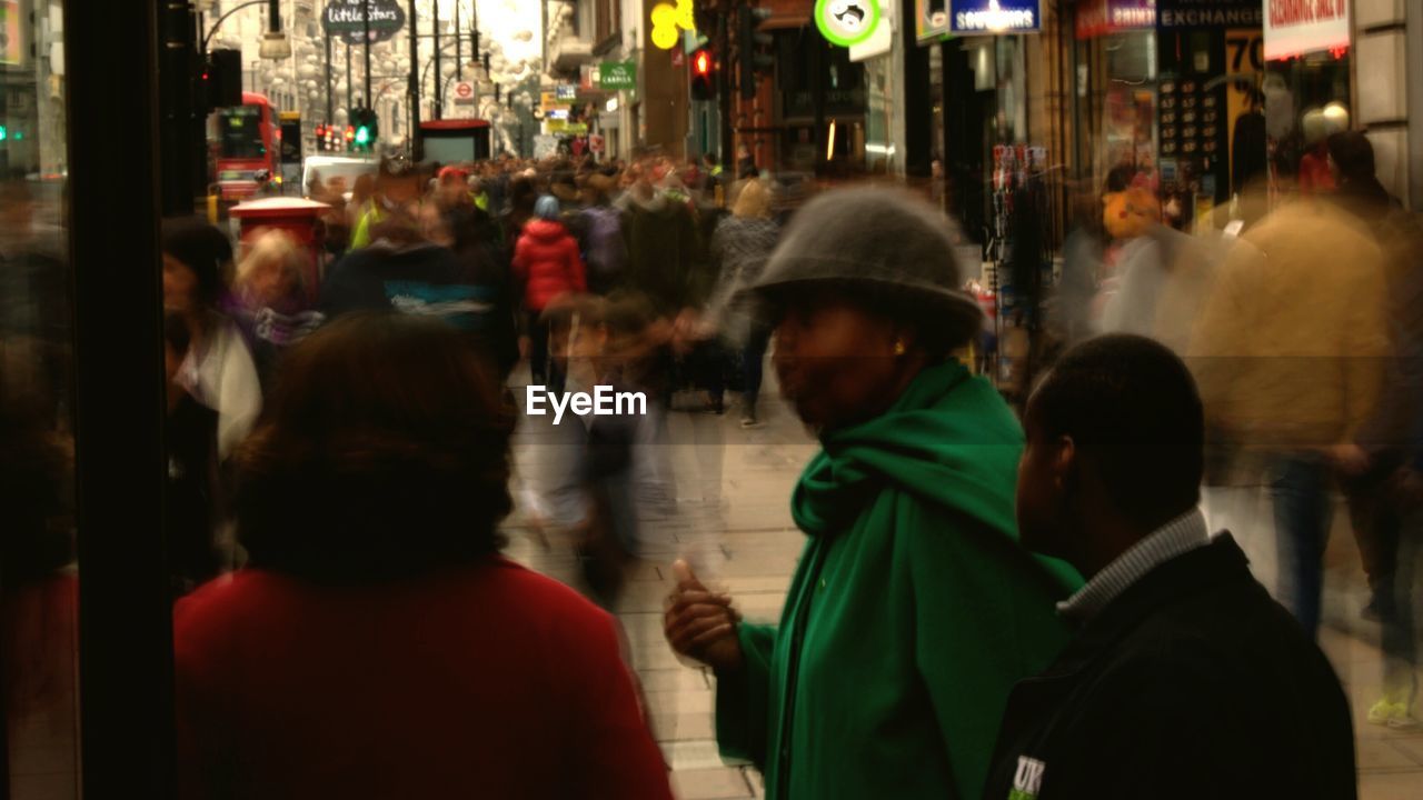 PEOPLE WALKING ON ILLUMINATED STREET