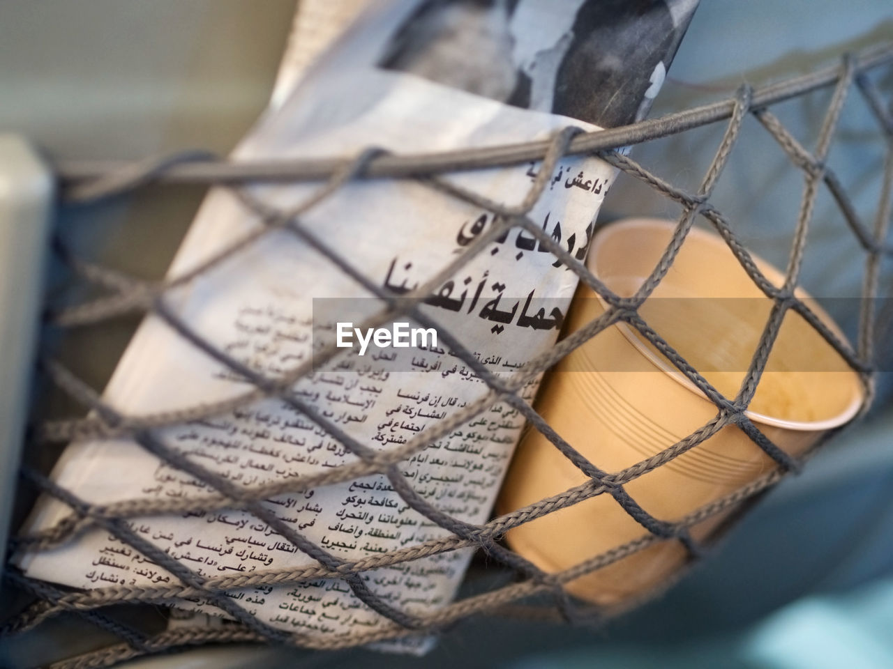 Close-up of newspaper and disposable cup in basket