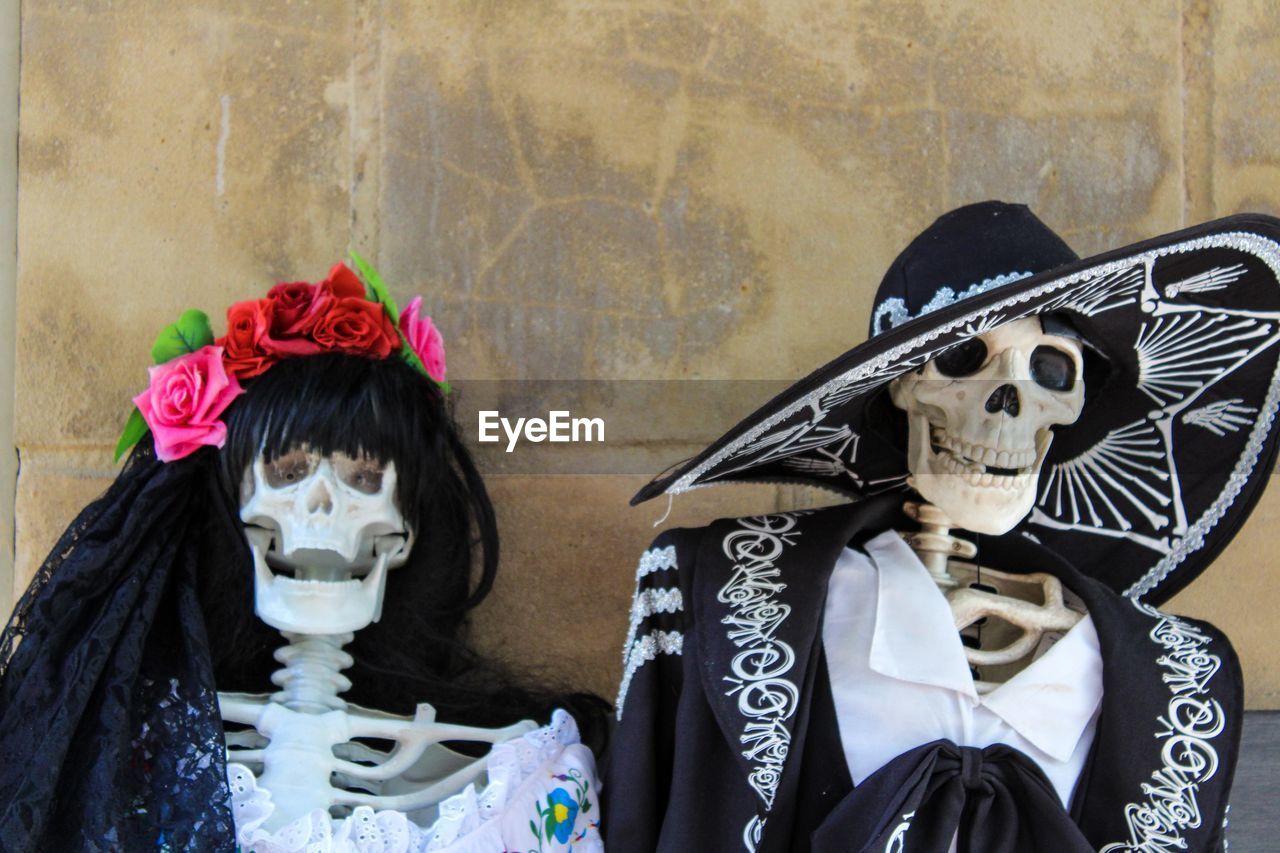 Skeletons in traditional clothing against wall