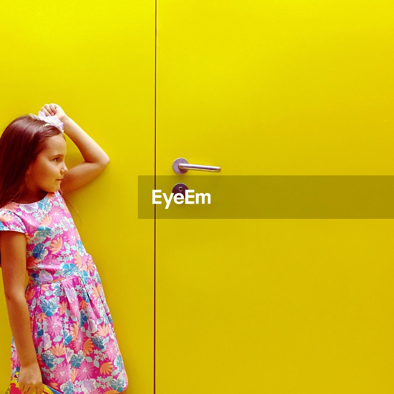 Side view of girl standing against yellow door