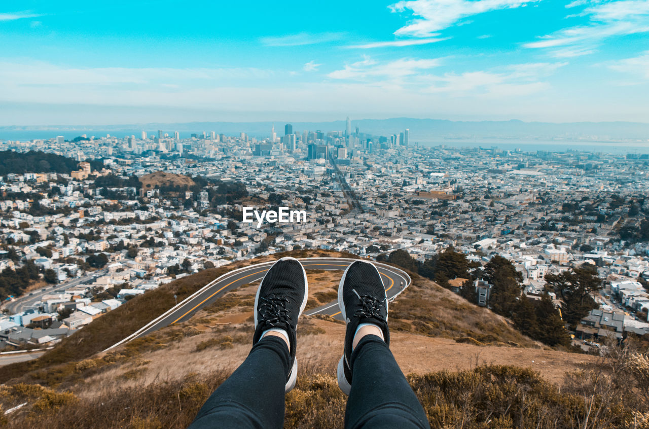 Low section of man over cityscape against sky