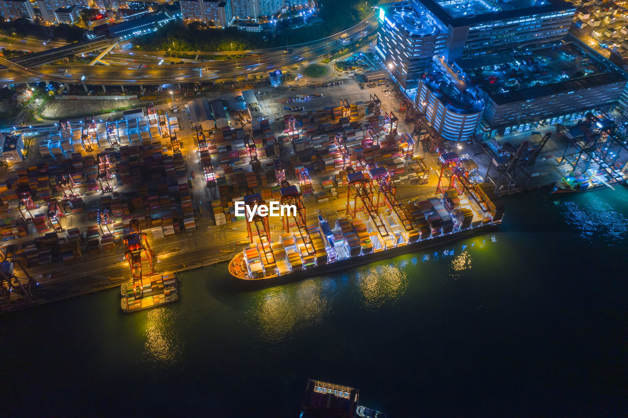 HIGH ANGLE VIEW OF ILLUMINATED CITY AT RIVERBANK