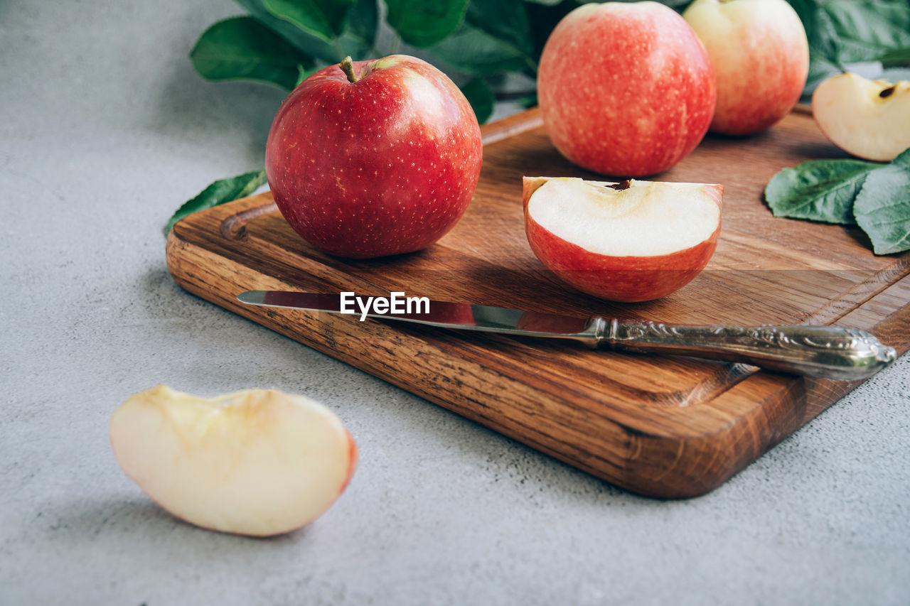 Front view of freshly harvested ripe red organic apples on wooden cutting board on table.