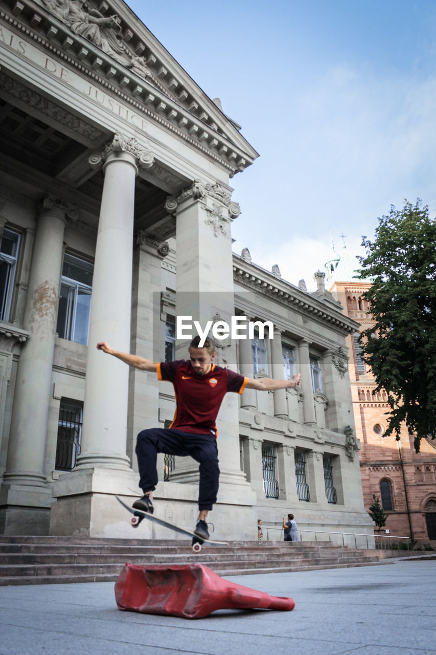 FULL LENGTH PORTRAIT OF SMILING MAN IN CITY AGAINST SKY