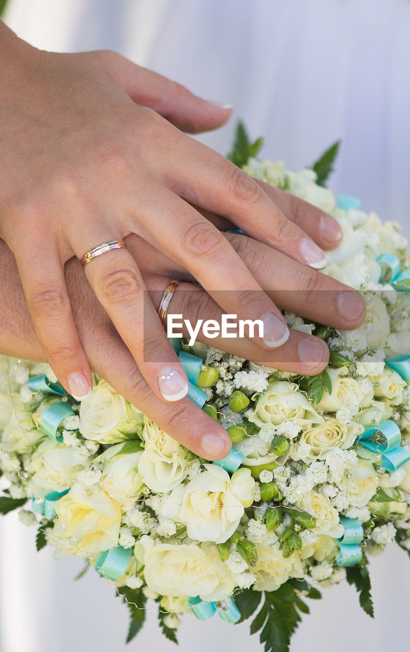 Cropped image of newlywed couple touching bouquet