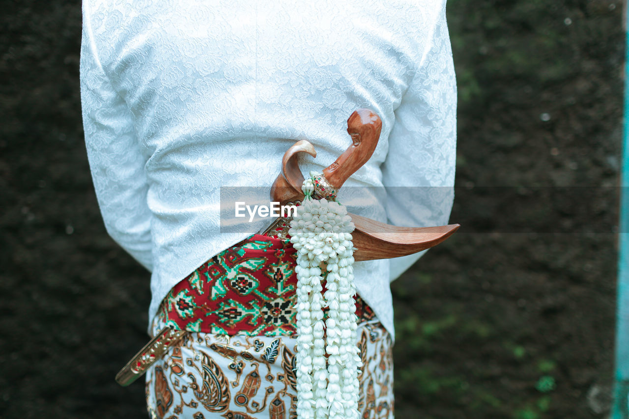 Midsection of bridegroom with dagger during wedding ceremony