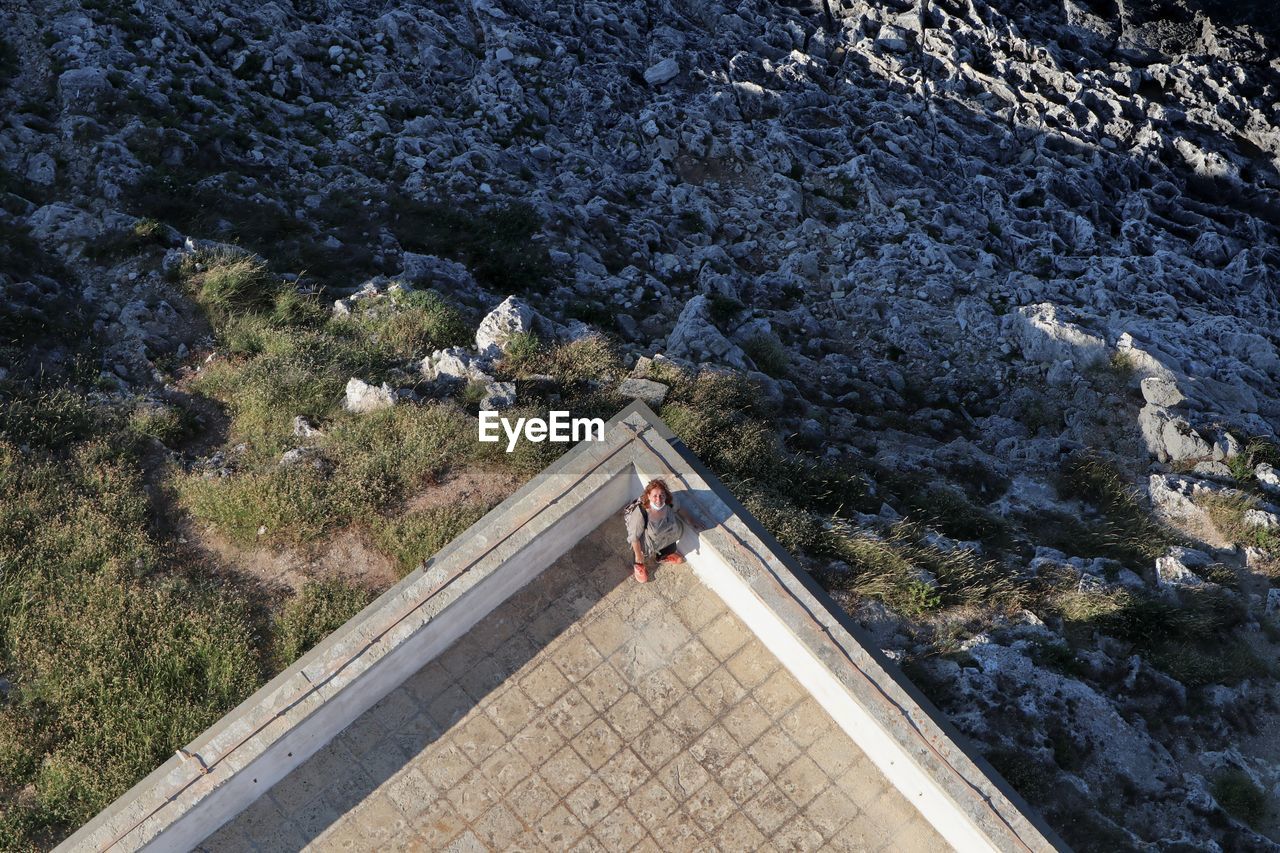 HIGH ANGLE VIEW OF PEOPLE ON ROCK AT SHORE