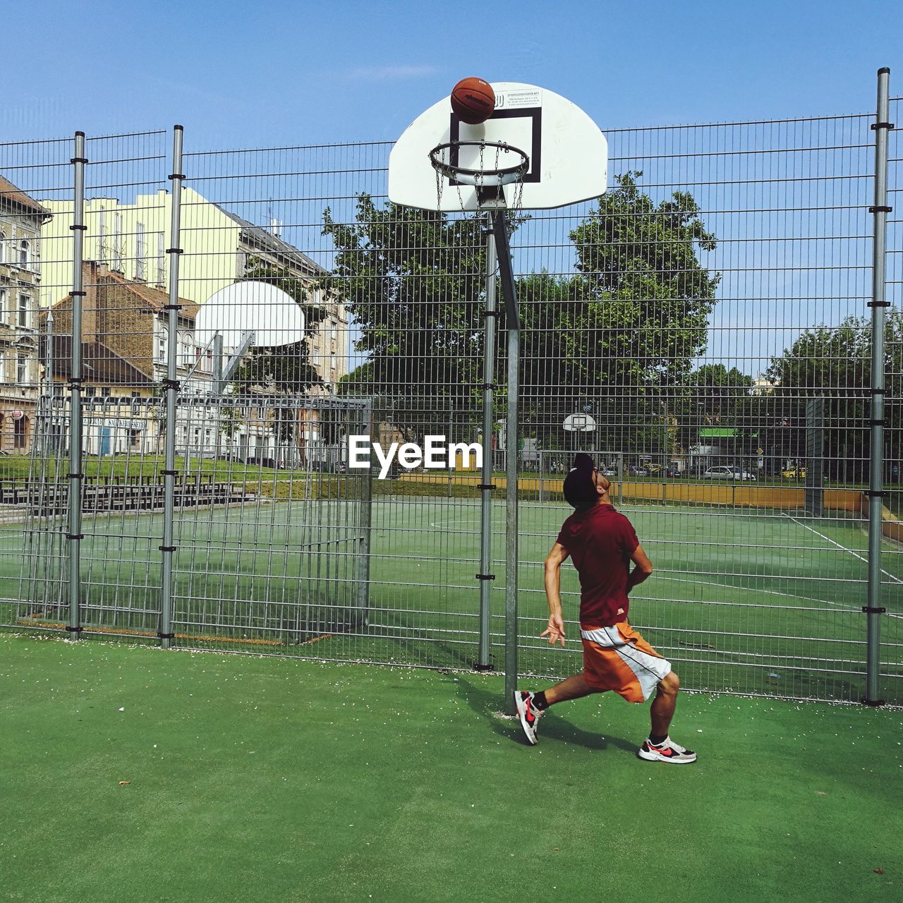 REAR VIEW OF MAN PLAYING SOCCER BALL ON FIELD