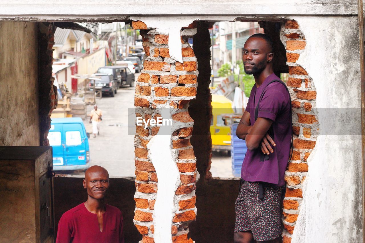 Portrait of men standing by old brick walls