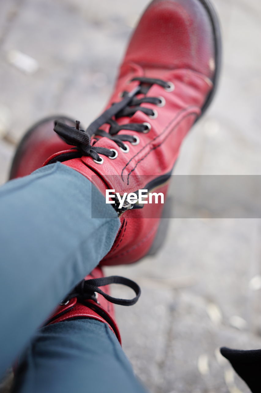 Low section of person wearing red shoes on footpath