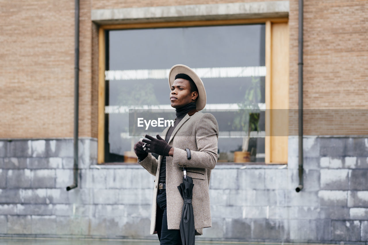 Portrait of elegant black man with grey coat in the street looking away