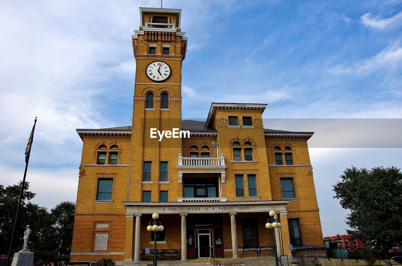 Low angle view of clock tower and courthouse against sky