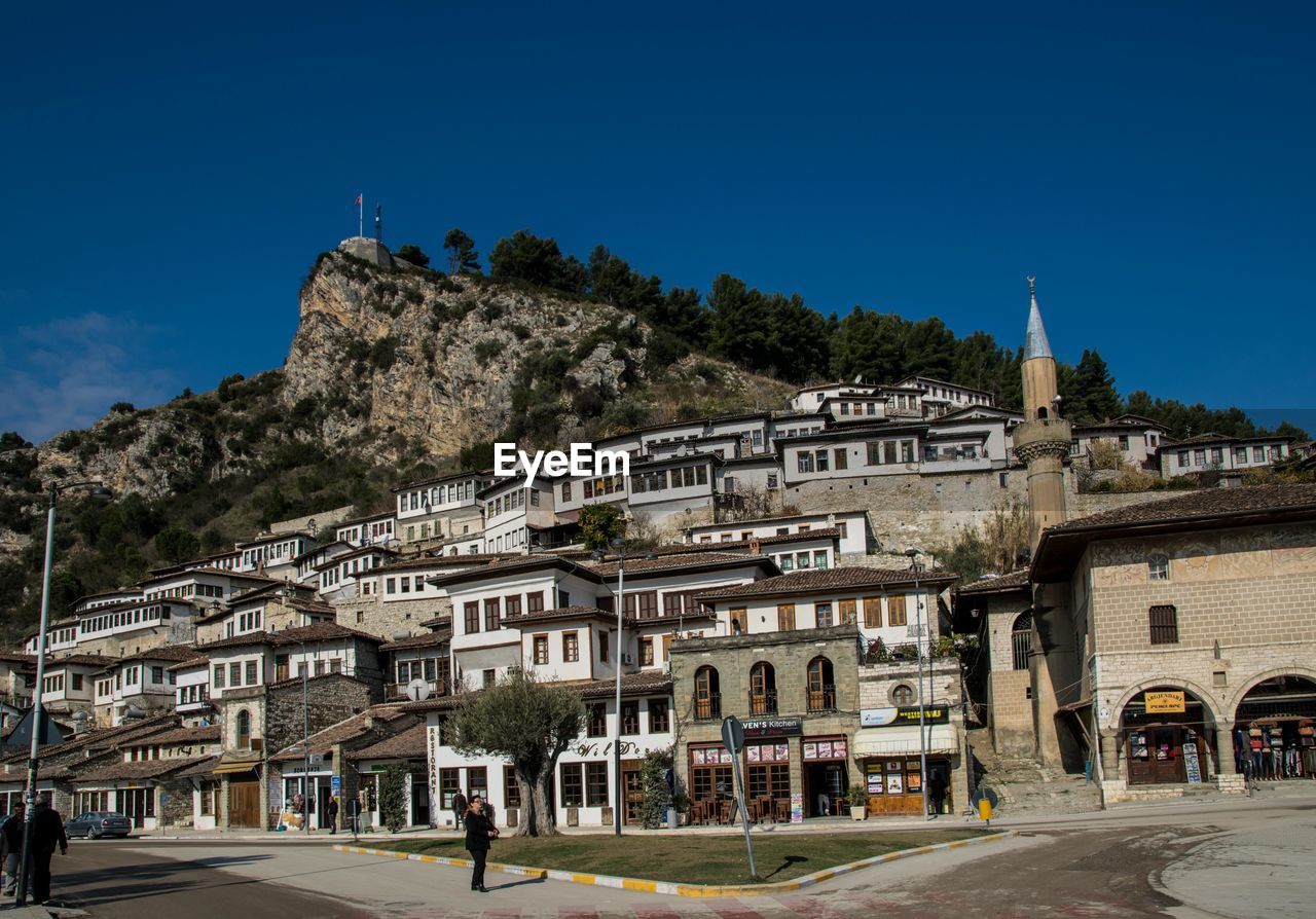 Buildings in city against clear blue sky