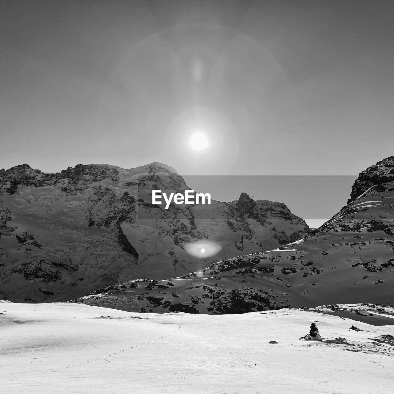 snow, mountain, scenics - nature, cold temperature, environment, sky, winter, landscape, beauty in nature, nature, mountain range, white, moon, black and white, tranquility, monochrome, land, tranquil scene, sun, snowcapped mountain, monochrome photography, travel, travel destinations, no people, non-urban scene, full moon, sunlight, outdoors, frozen, winter sports, tourism, extreme terrain, adventure, vacation