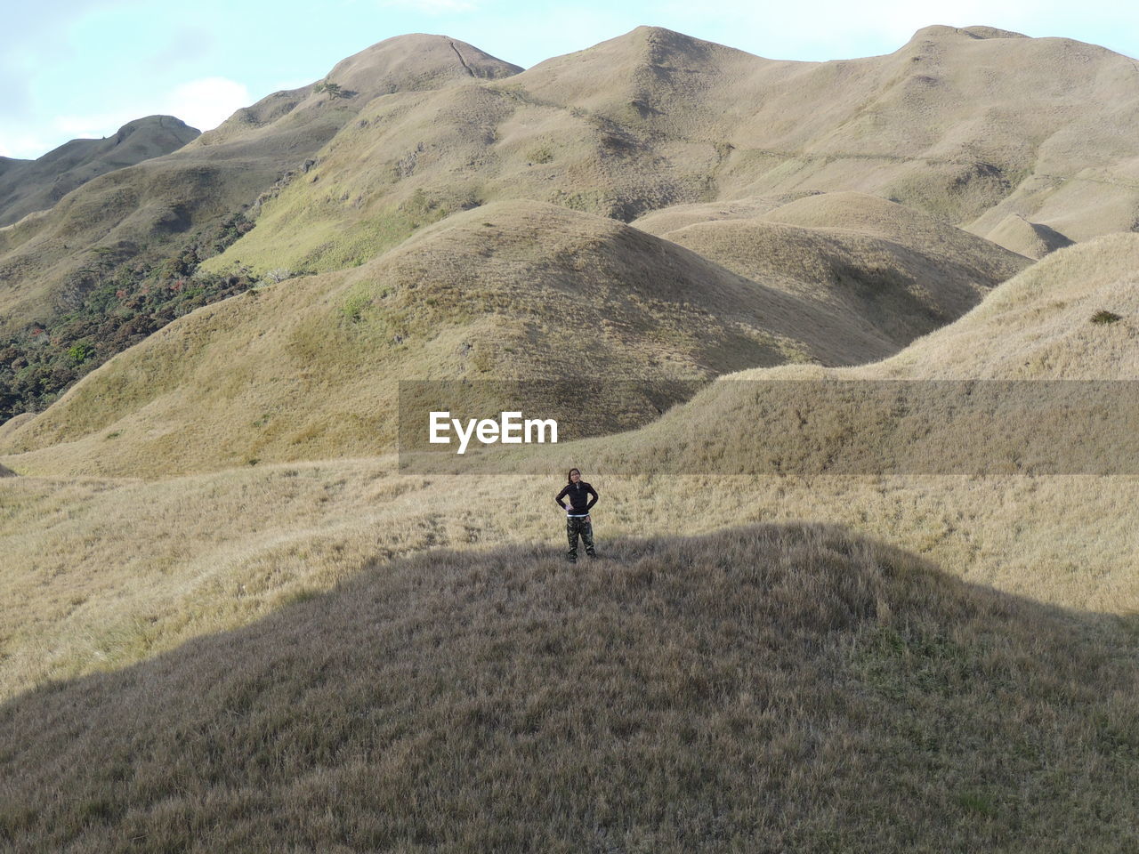 Mid distance view of woman standing on grassy mountain