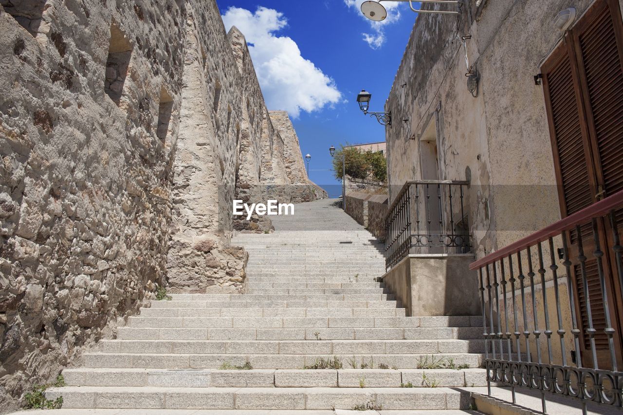 Steps amidst houses and stone wall