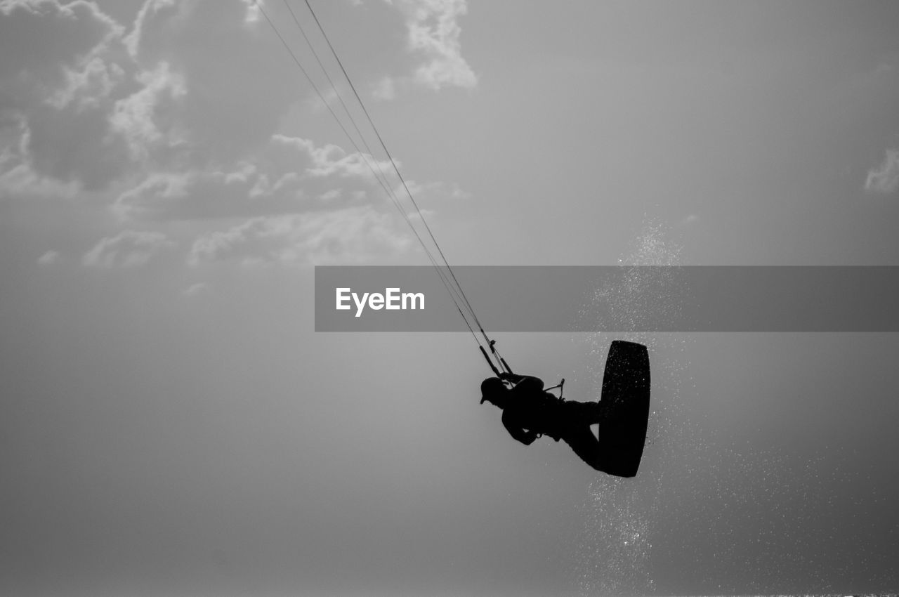 Low angle view of man kiteboarding against sky