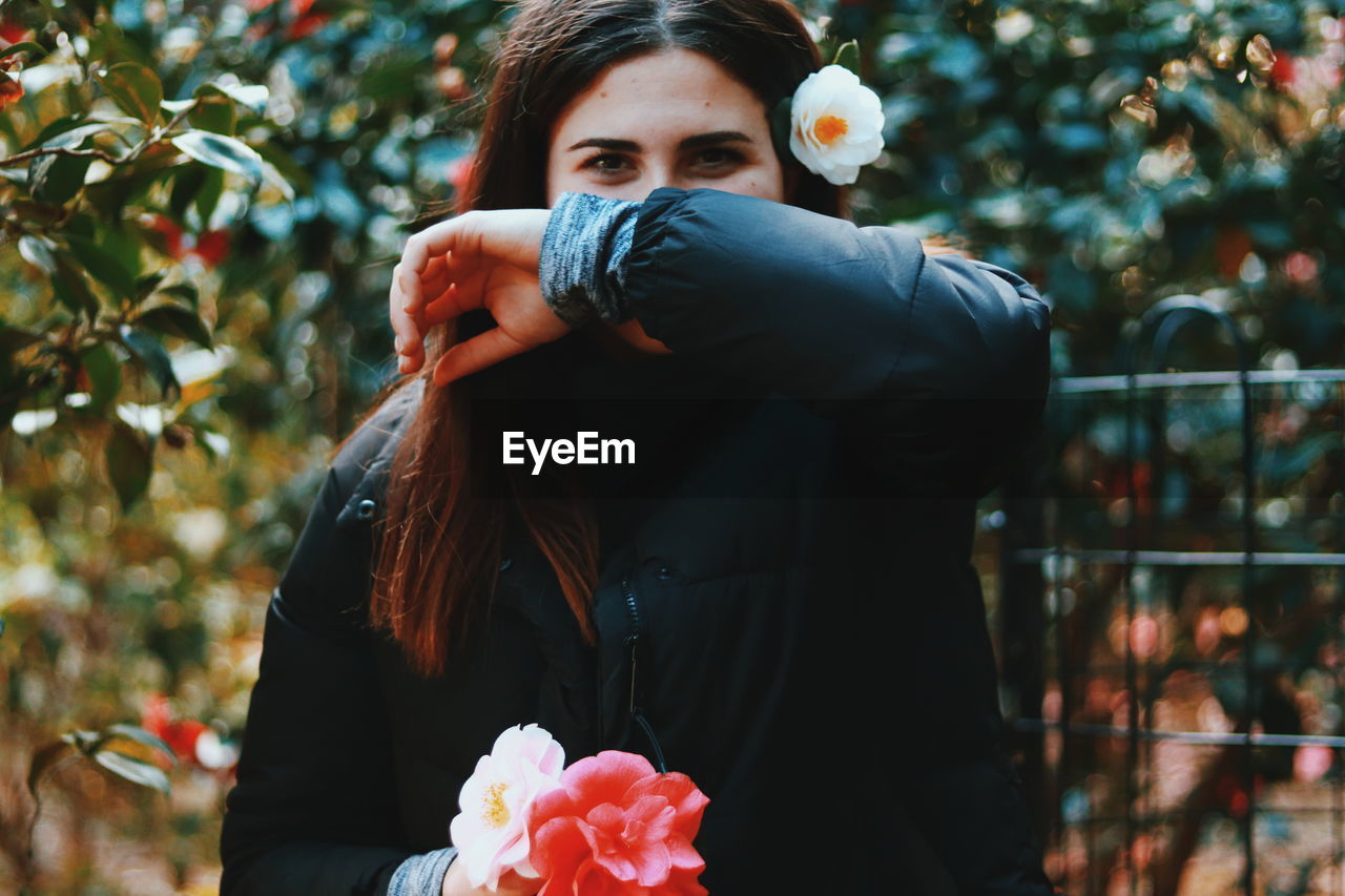 Portrait of woman wearing flower against tree