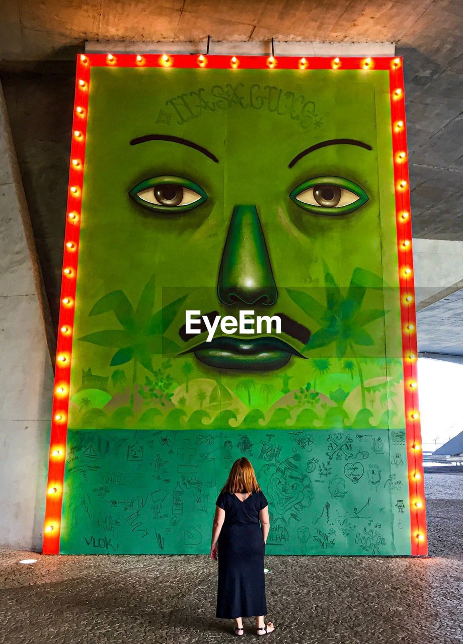 PORTRAIT OF WOMAN STANDING AGAINST GRAFFITI WALL