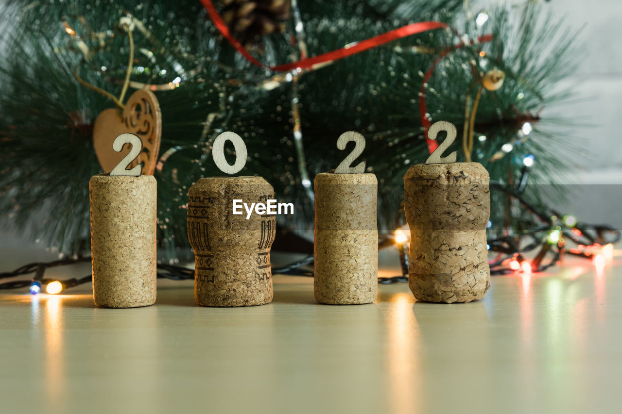  christmas tree with garland lights, there are champagne and wine corks with wooden numbers 2022