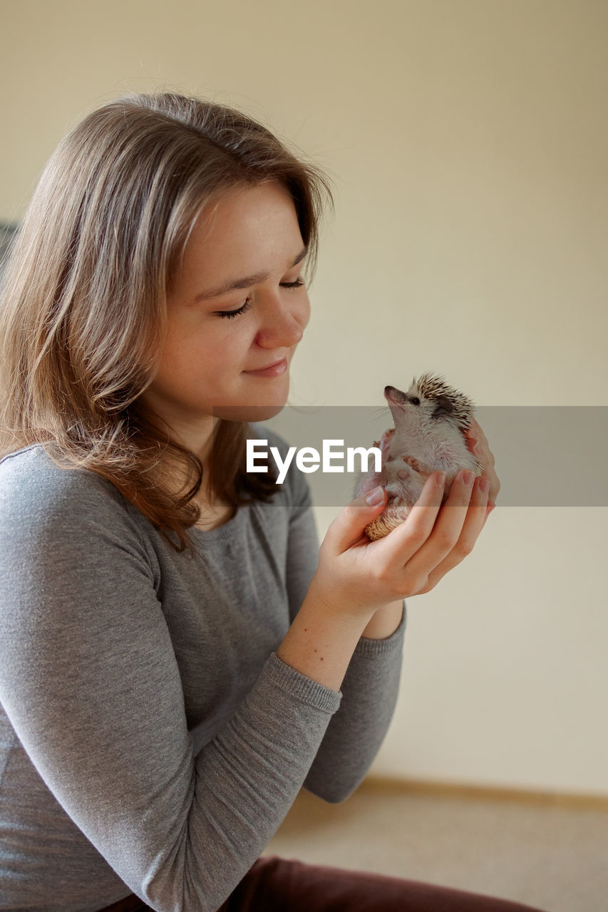 Girl holds cute hedgehog in her hands. portrait of pretty curious muzzle of animal. favorite pets. 