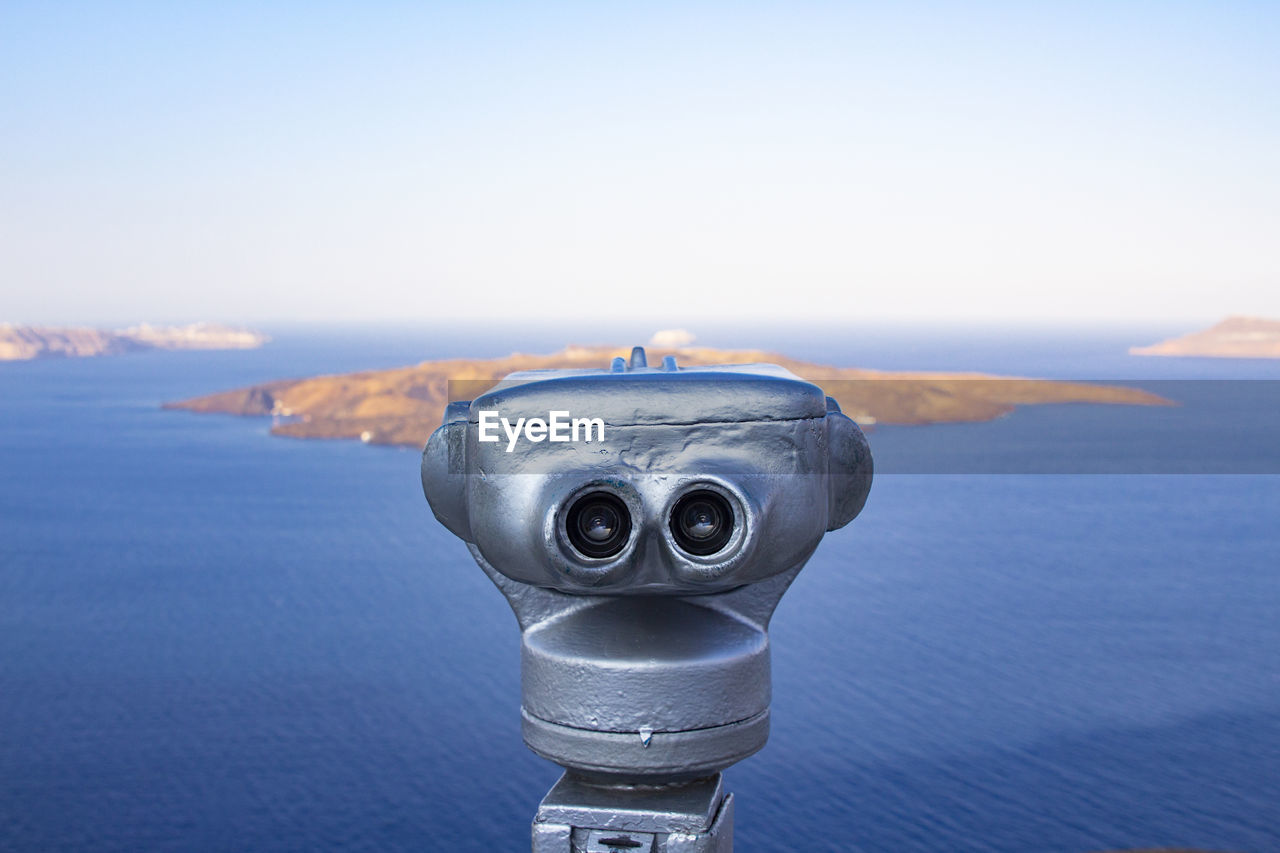 Close-up of coin-operated binoculars by sea against sky