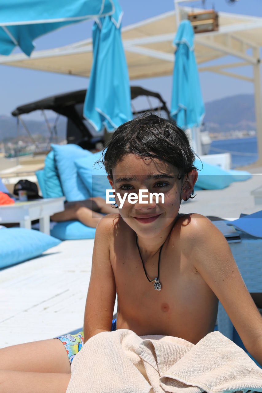 Boy looking away while sitting at beach