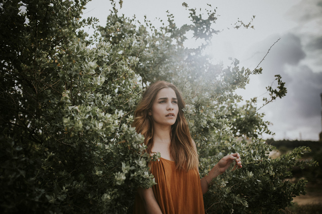 Portrait of young woman against trees