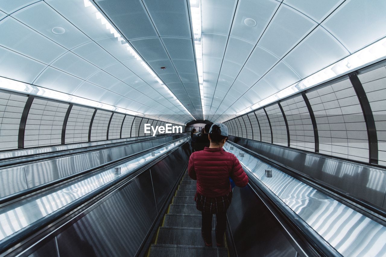 Rear view of woman on escalator at subway station