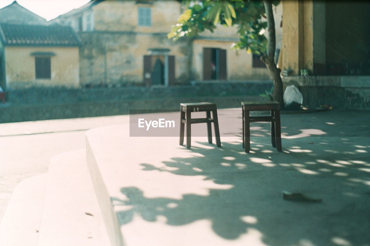 EMPTY CHAIRS AND TABLE IN YARD OF BUILDING