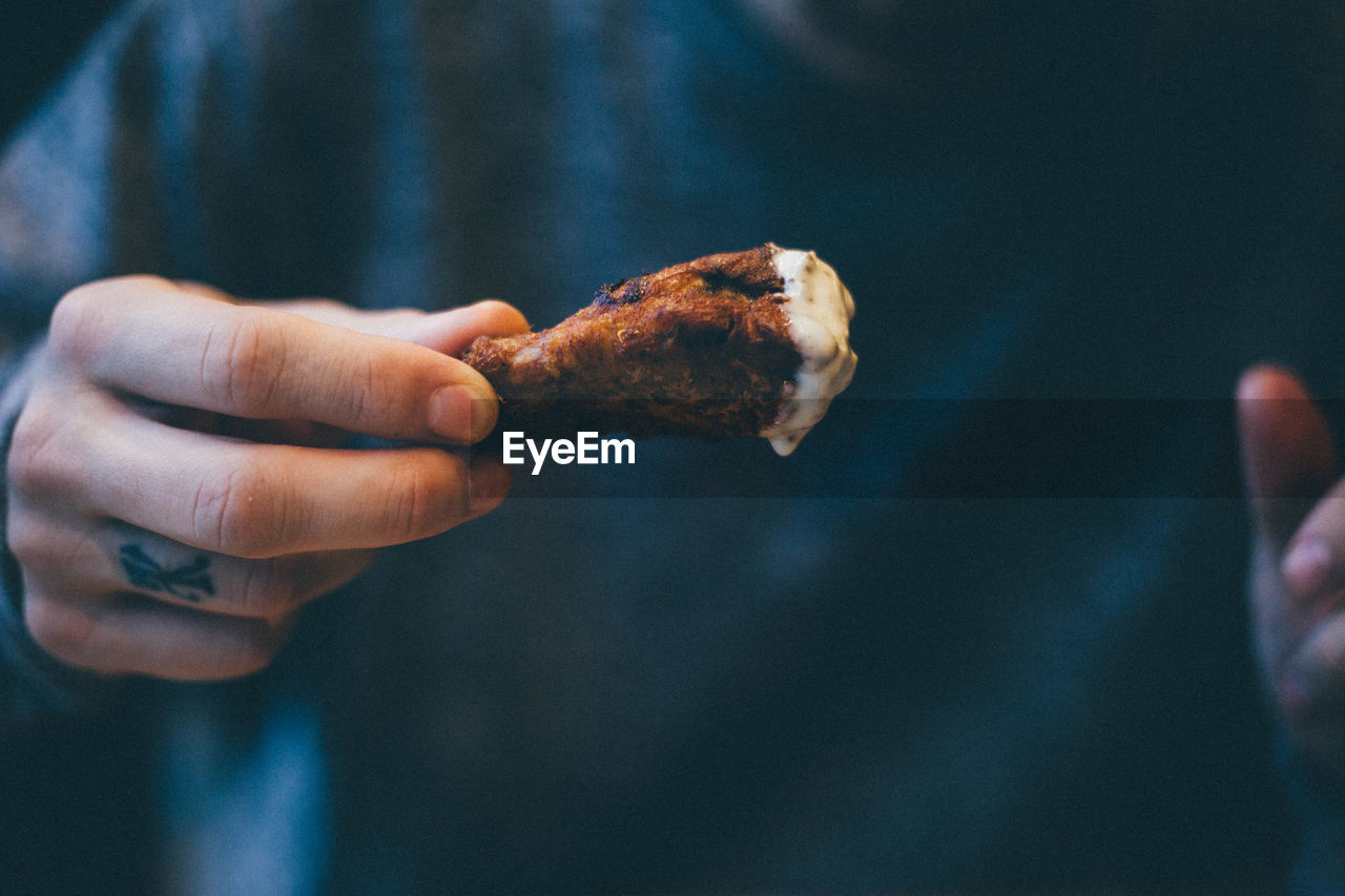 Midsection of man eating chicken meat