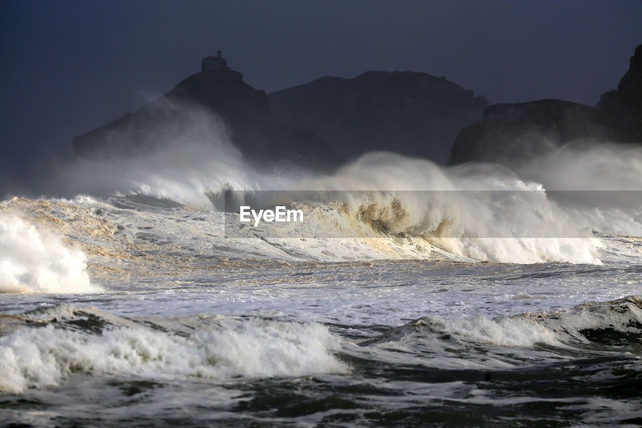 Waves splashing in sea against clear sky