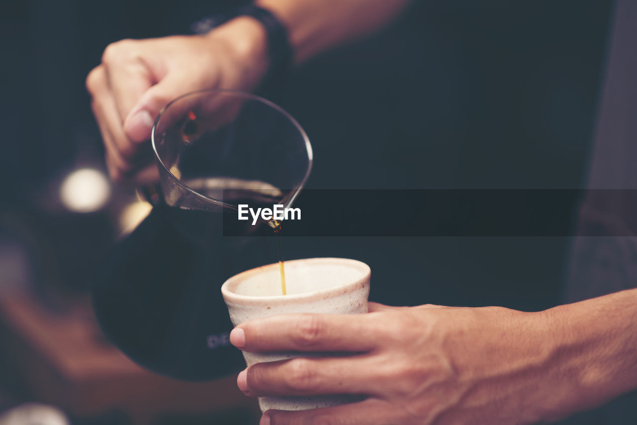 Cropped image of man pouring black coffee in mug