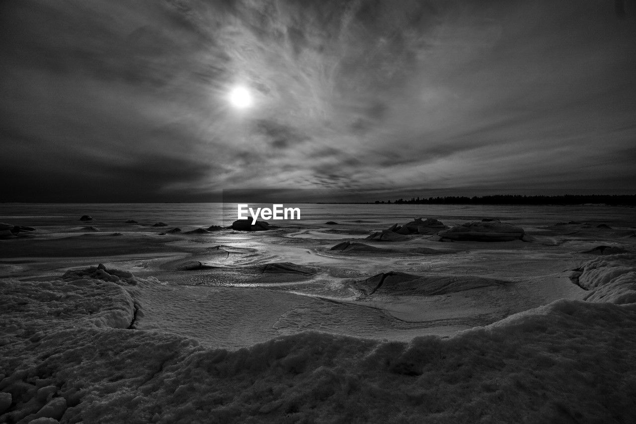 sky, sea, water, beach, land, cloud, darkness, black and white, scenics - nature, wave, nature, beauty in nature, horizon, monochrome, monochrome photography, ocean, horizon over water, light, environment, coast, moonlight, sand, tranquility, night, wind wave, landscape, no people, moon, outdoors, motion, tranquil scene, dramatic sky, seascape, coastline, travel destinations, rock, black, travel, dusk