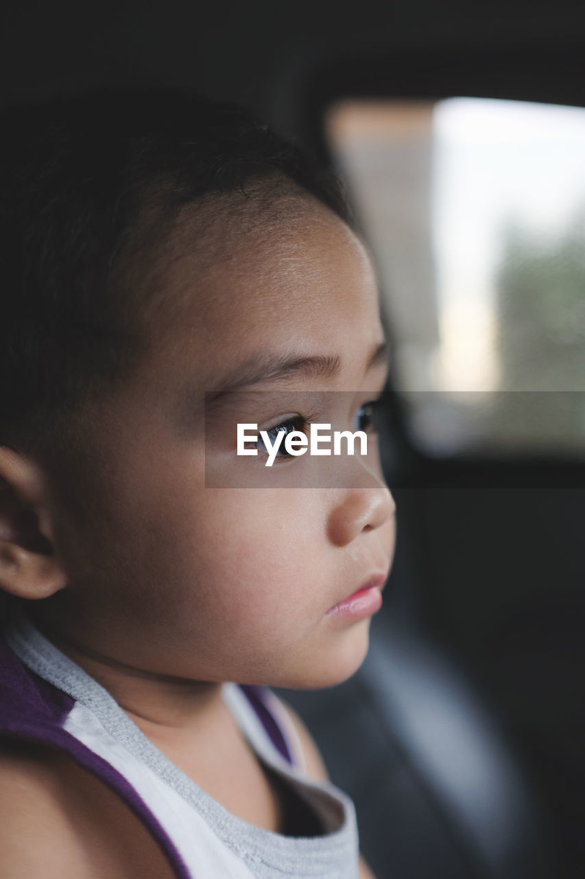 Close-up of cute boy looking away while sitting in car