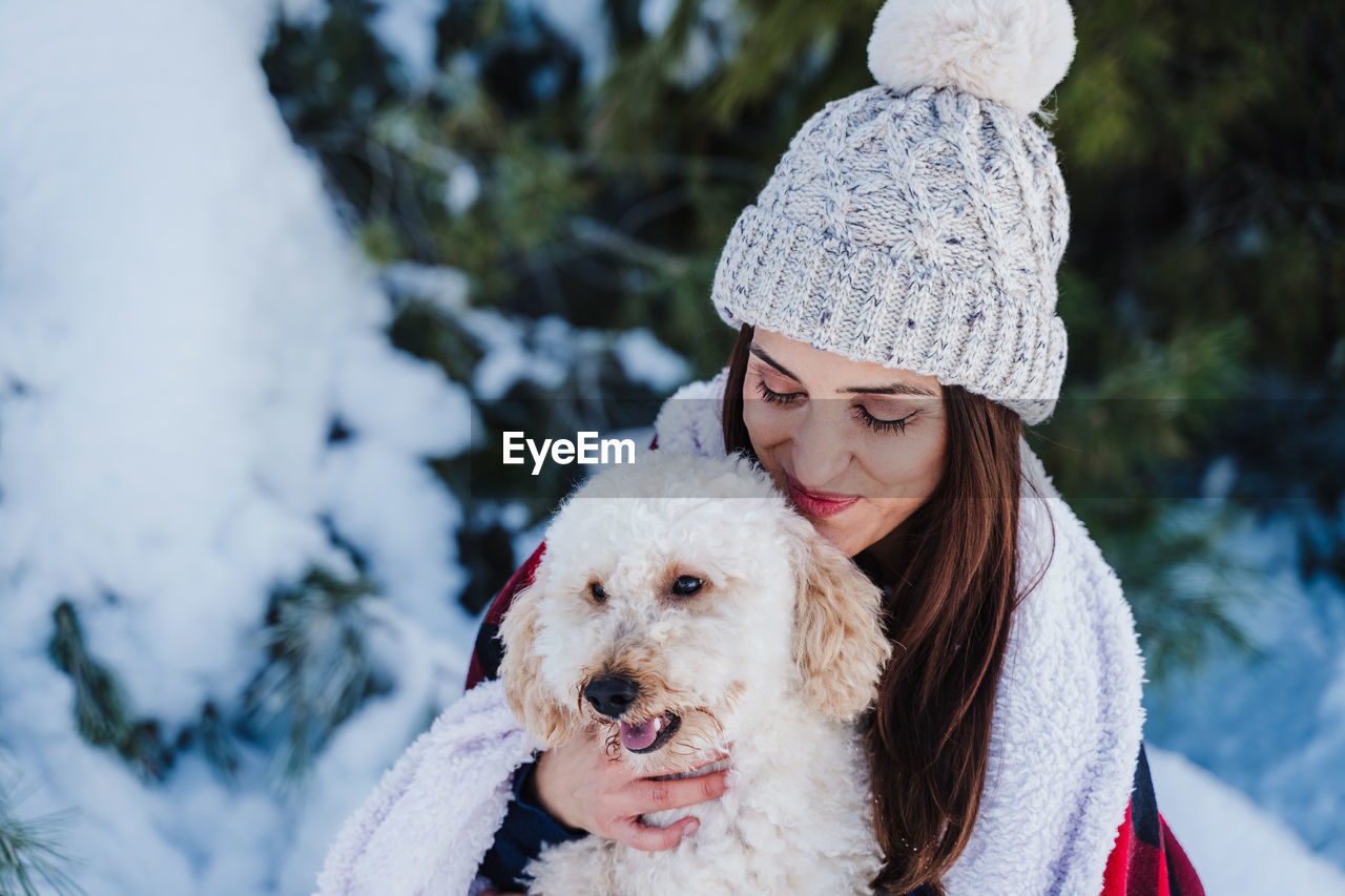 CLOSE-UP OF WOMAN WITH DOG IN SNOW