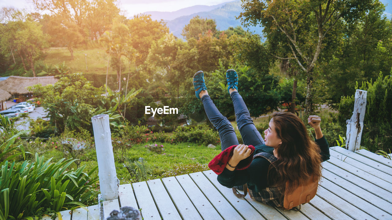 SIDE VIEW OF WOMAN SITTING ON PLANTS