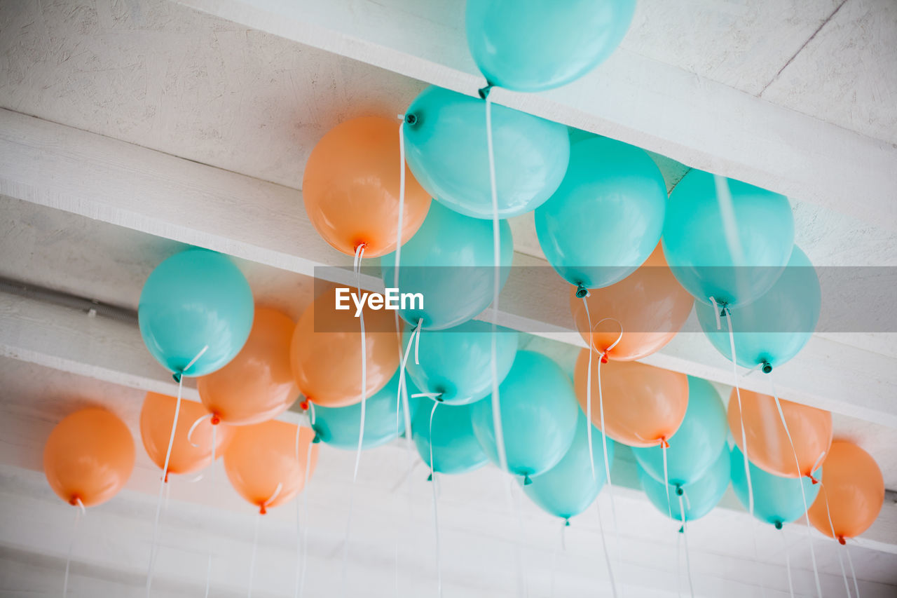 Orange and green balloons with white ribbons on the ceiling