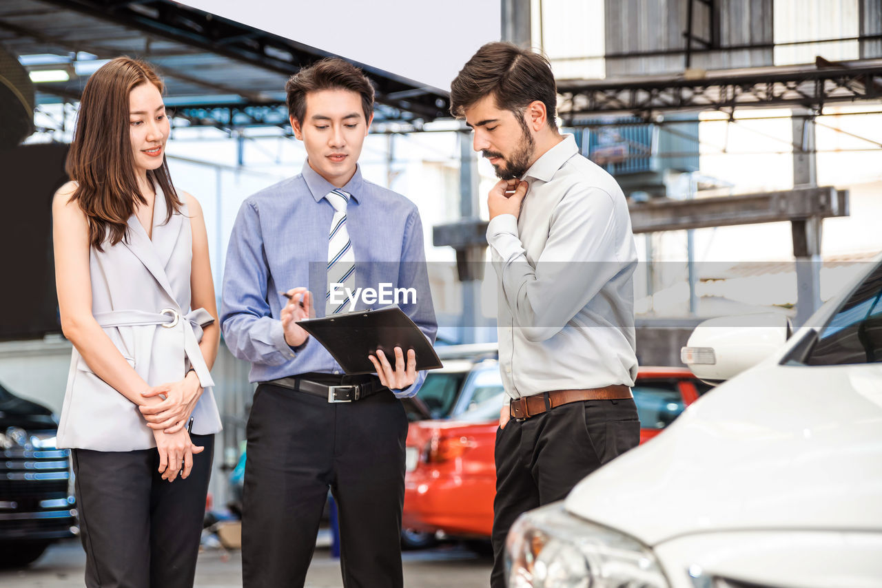 Car dealership. the asian salesman checked the list with the middle east customer before hand over.