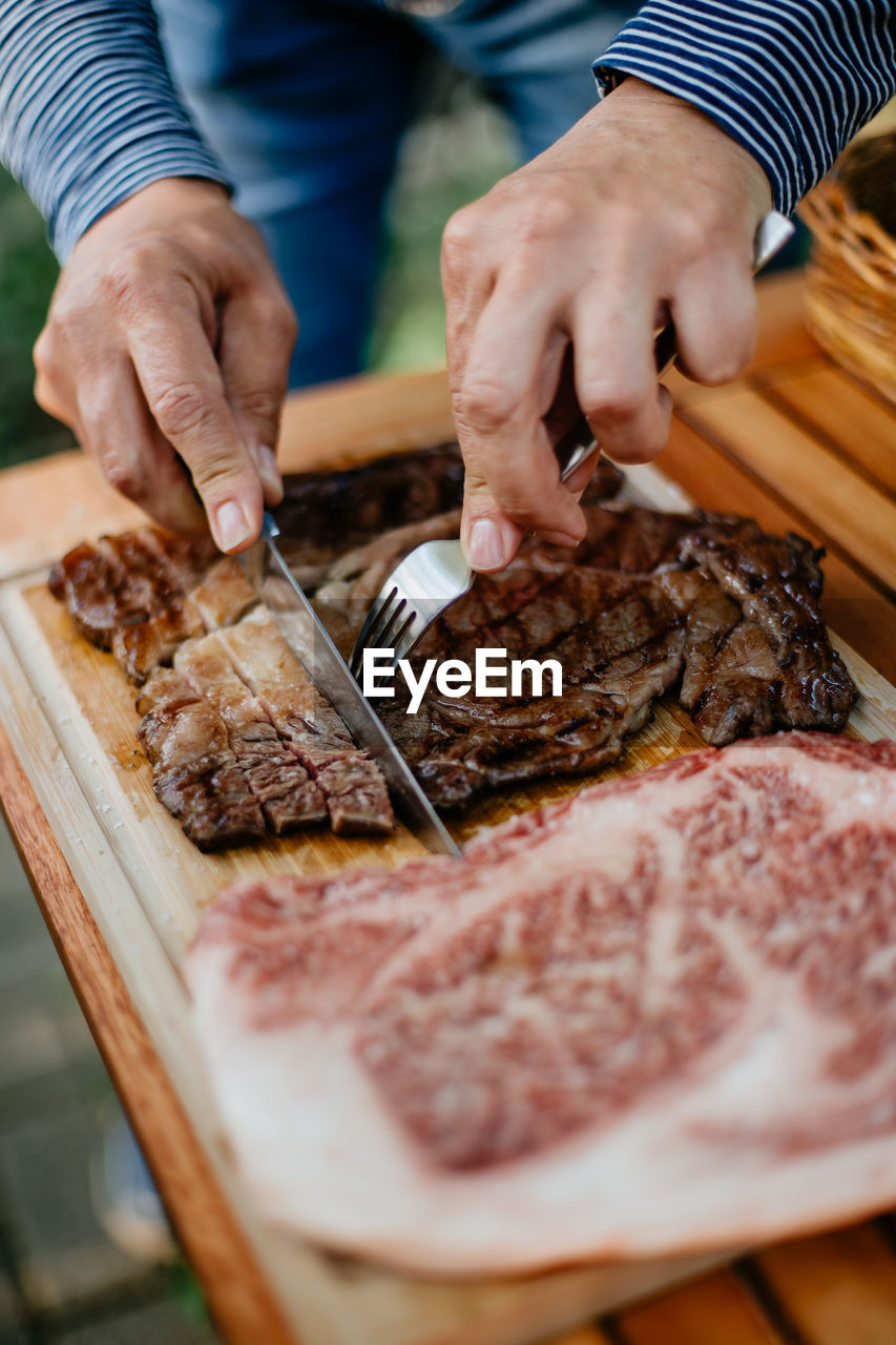 Midsection of person cutting meat