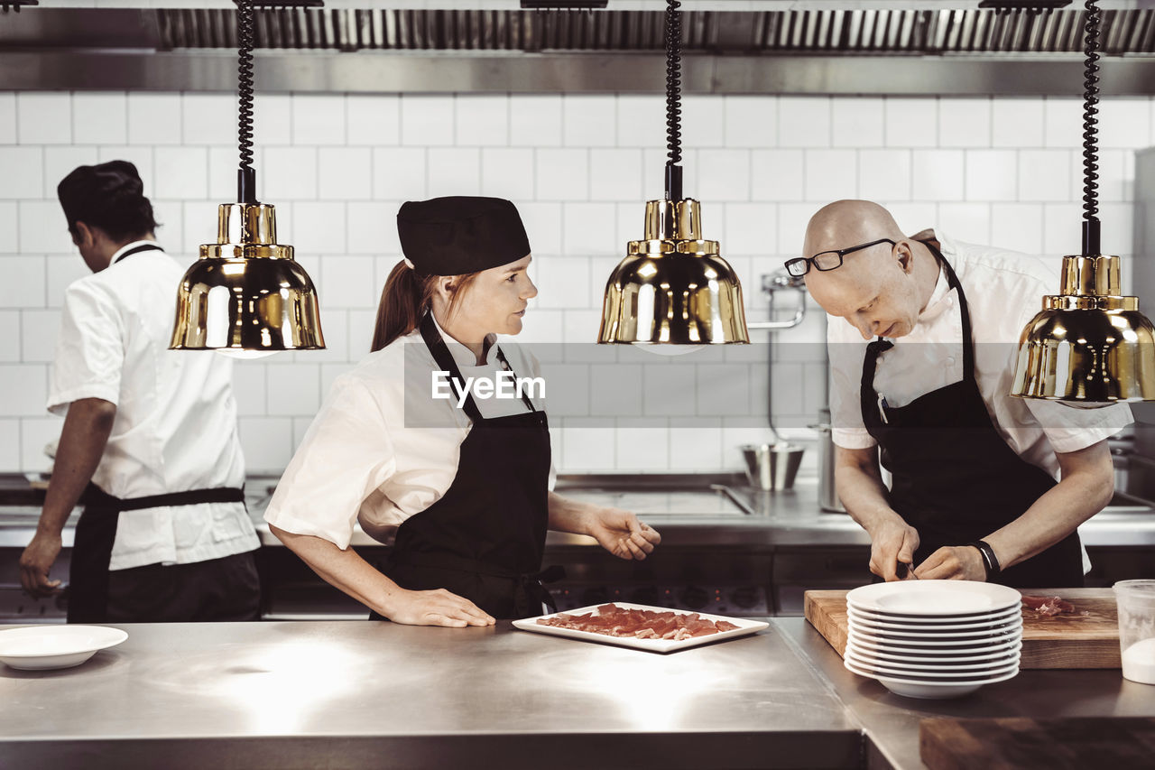 Male and female chefs working in commercial kitchen