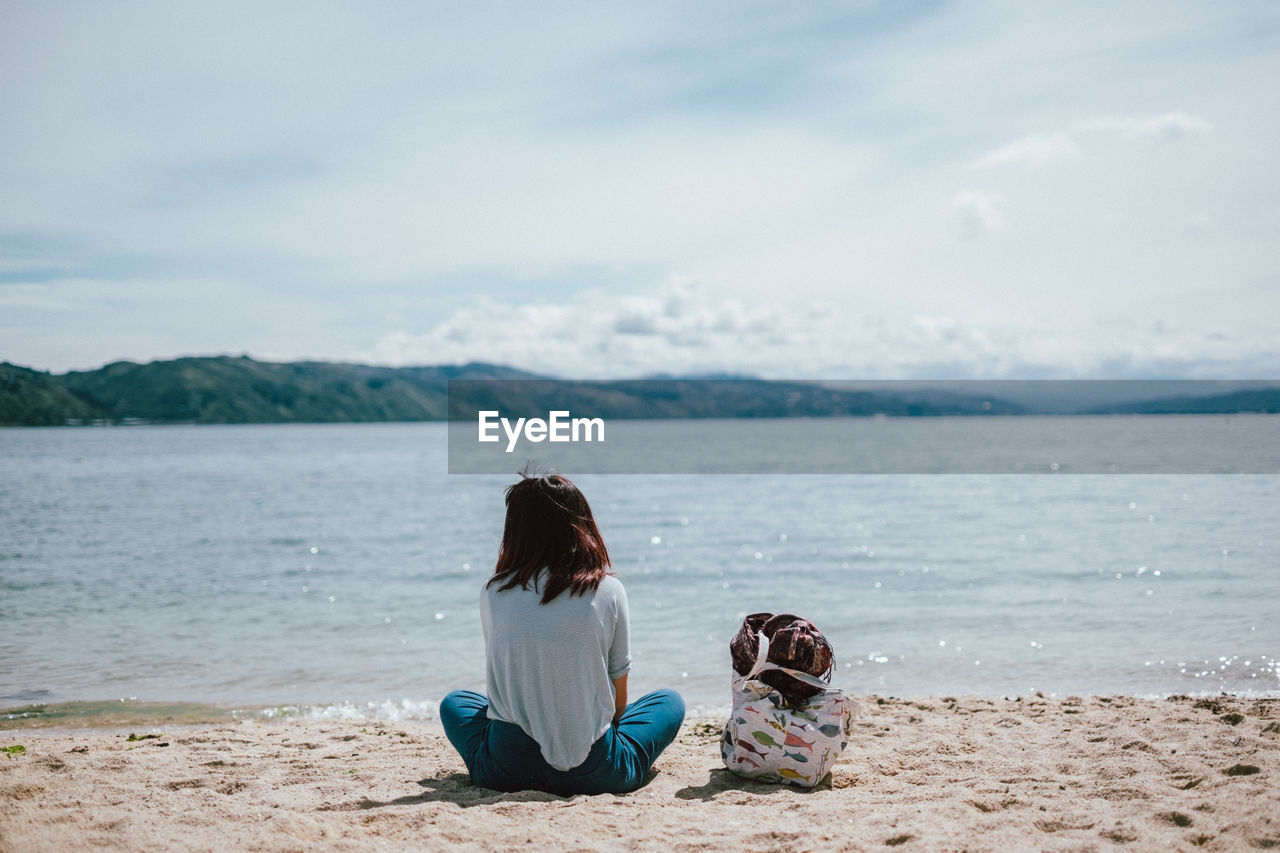 Rear view of woman sitting on beach