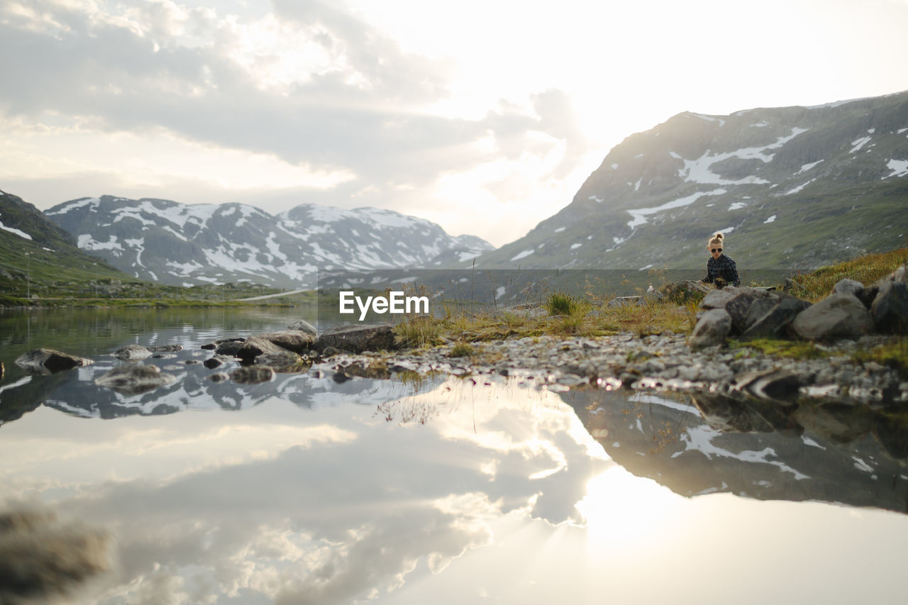 Woman sitting at lake in mountains