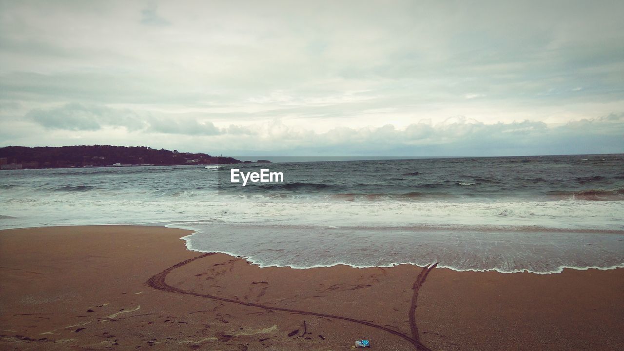 Scenic view of beach against cloudy sky