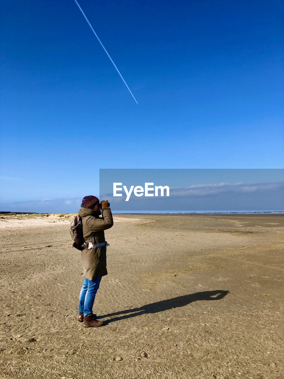 Full length of woman on beach against blue sky