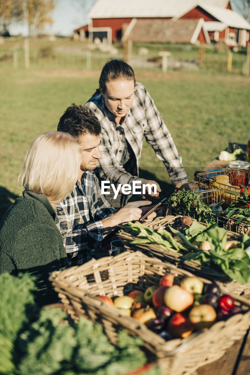 Male and female farmers using digital tablet with organic vegetables on table