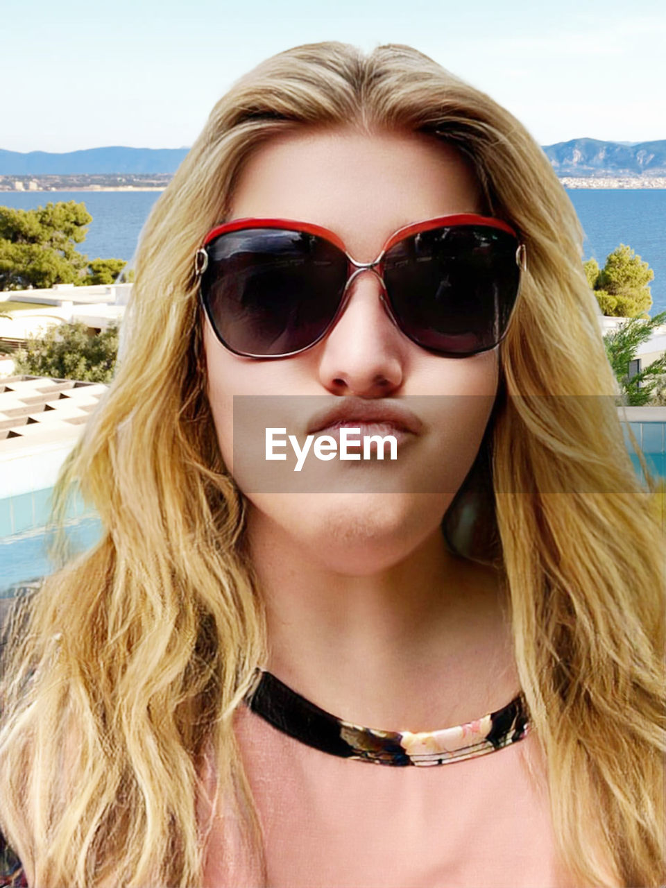 fashion, sunglasses, glasses, portrait, blond hair, human hair, long hair, hairstyle, one person, young adult, women, adult, front view, headshot, vision care, eyewear, fashion accessory, summer, brown hair, day, nature, beach, leisure activity, lifestyles, water, land, outdoors, looking at camera, human face, sky, clothing, sunlight, goggles, trip, close-up, holiday, vacation, sea, person, cool attitude