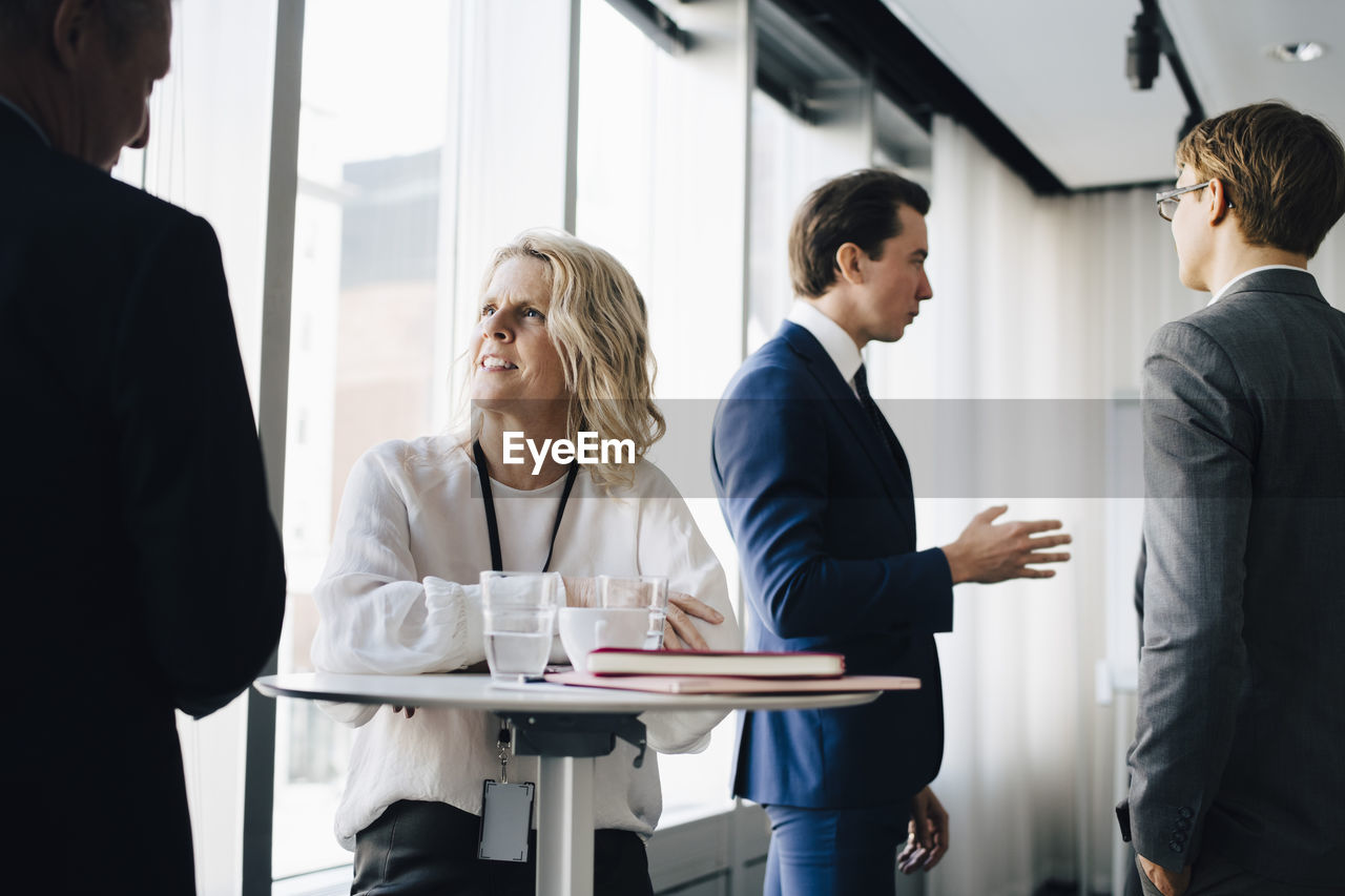 Female entrepreneur talking to colleague while coworker standing in background at workplace