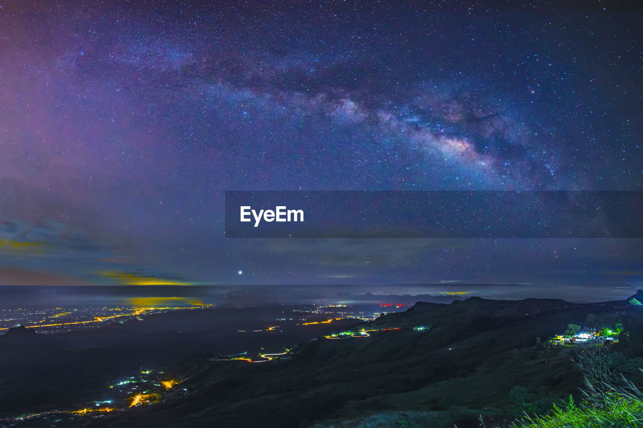 AERIAL VIEW OF ILLUMINATED CITYSCAPE AGAINST STAR FIELD